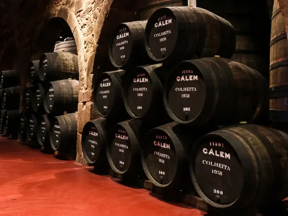 Barricas de vino de Oporto Cálem alineadas en una bodega tradicional de piedra.
