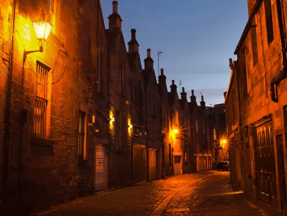 Callejón de Edimburgo al anochecer, iluminado por farolas