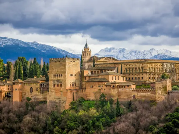 La Alhambra domina la ciudad de Granada, con sus imponentes murallas y torres, rodeada de jardines que reflejan su esplendor.