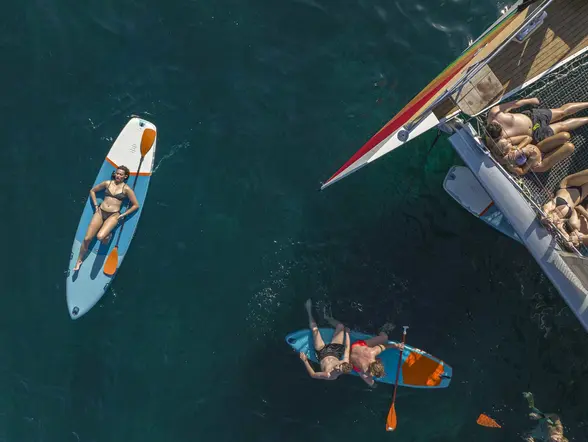 Gente disfrutando del sol mientras se relajan sobre tablas de kayak, flotando en las aguas de la isla de Mallorca.