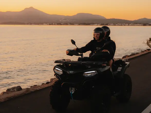 Dos personas montan en quad por la costa mallorquina al atardecer