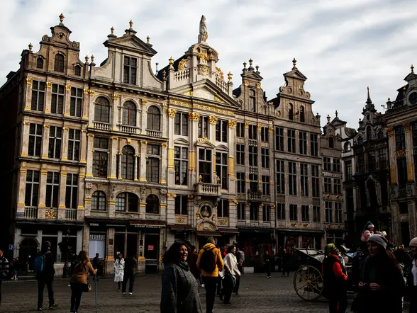 Personas paseando por la famosa Grand Place de Bruselas, rodeada de históricos edificios ornamentados.