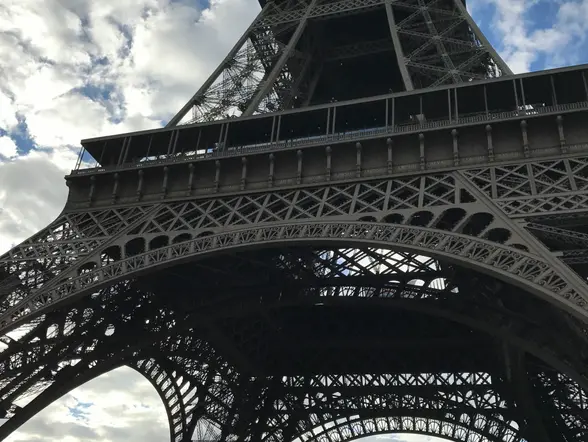 Vista desde la base de la Torre Eiffel en París, Francia, mostrando la estructura metálica contra un cielo parcialmente nublado.