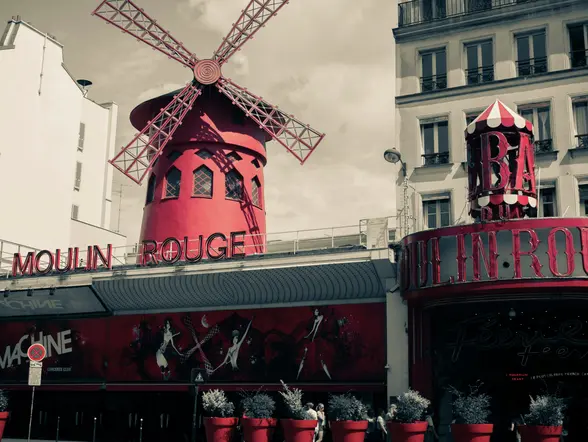 Foto en tonos rojos y negros del Moulin Rouge, un icónico molino de viento en París.