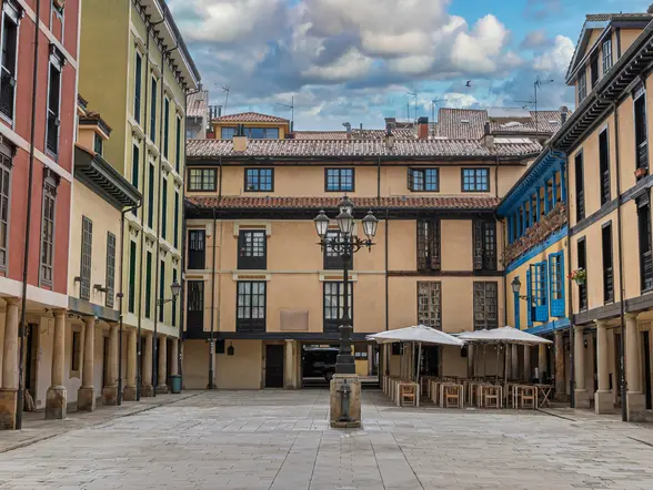 Plaza del Fontán en Oviedo, Asturias, con fachadas de colores, soportales tradicionales y una estatua en primer plano.