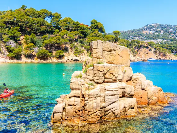 Kayakista junto a rocas en aguas cristalinas de Menorca, Baleares