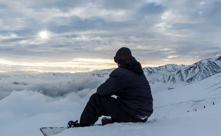 Chico sentando contemplado las vistas de las montañas.