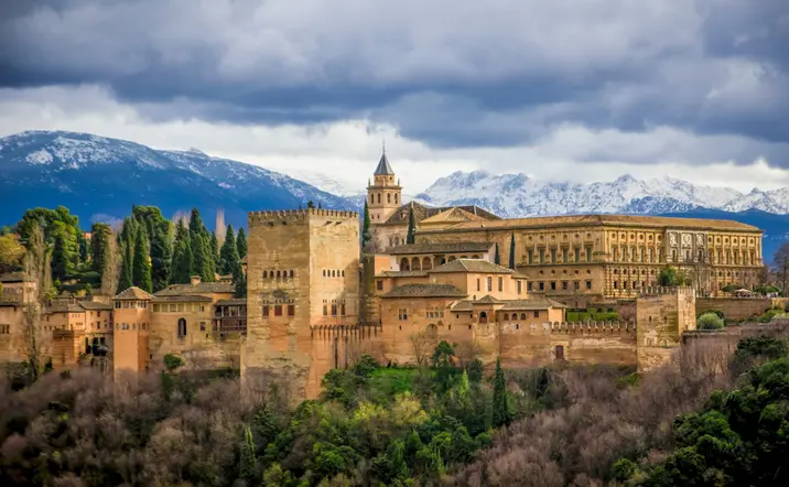 La Alhambra domina la ciudad de Granada, con sus imponentes murallas y torres, rodeada de jardines que reflejan su esplendor.