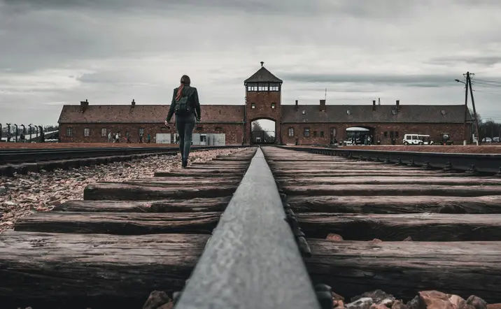 Persona caminando por las vías del tren hacia la entrada de ladrillo del campo de concentración de Auschwitz-Birkenau.
