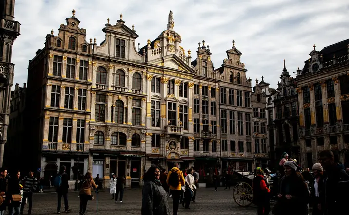 Personas paseando por la famosa Grand Place de Bruselas, rodeada de históricos edificios ornamentados.