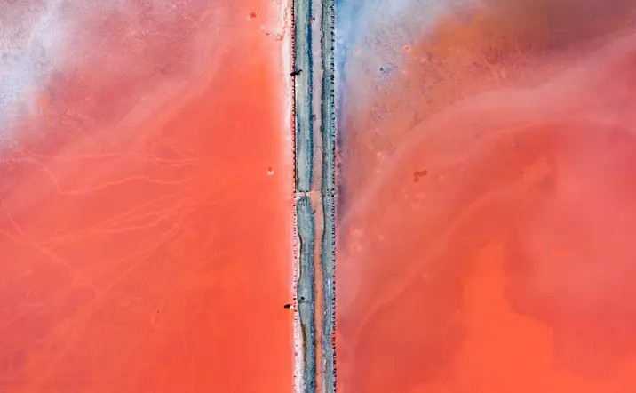 Vista aérea de la Laguna Rosa de Torrevieja con una carretera que divide las intensas aguas rosadas.