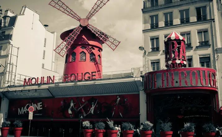 Foto en tonos rojos y negros del Moulin Rouge, un icónico molino de viento en París.